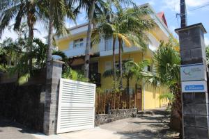 a yellow house with palm trees in front of it at Le Rubinjo - Appartement d'hôtes in Saint-Benoît