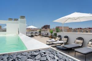 a rooftop patio with a pool and chairs and an umbrella at Limehome Sevilla Calle Torcuato Luca de Tena - Digital Access in Seville +42 photos