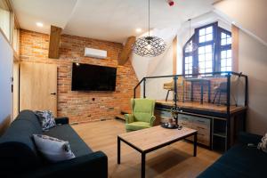 a living room with a couch and a brick wall at Apartamenty Rynek 13 in Grudziądz +56 photos