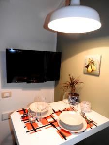 a table with plates and wine glasses and a flat screen tv at Delight Loft in Rovinj