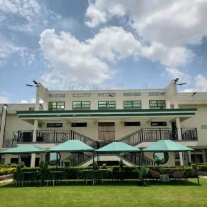 a large building with green umbrellas in front of it at Oodles garden in Nairobi