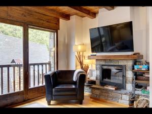 een woonkamer met een stoel en een televisie boven een open haard bij LIAT de Alma de Nieve in Bagergue