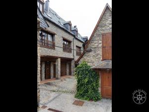 een groot bakstenen gebouw met houten deuren en een hek bij LIAT de Alma de Nieve in Bagergue