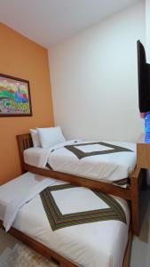 three beds in a room with a tv on a wall at The Cabin Hotel Sidoarum in Sleman