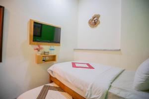 a room with a bed and a flat screen tv at The Cabin Hotel Sidoarum in Sleman