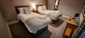 due letti in una stanza d'albergo con asciugamani sopra di The Royal Oak, Settle a Settle