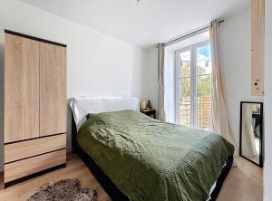 a bedroom with a bed and a dresser and a window at Appartement-Terrasse in Montbéliard