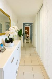 einen weißen Flur mit Blumen in einer Vase auf dem Tresen in der Unterkunft Comfortable and bright bedroom, in Étrembières