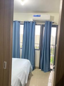 a bedroom with blue curtains and a bed and a window at Shore 2 tower 2 in Manila