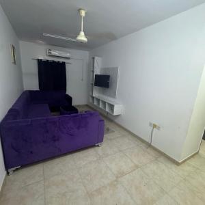 a living room with a purple couch and a tv at Ruslan in Muscat