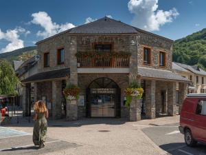 a woman walking in front of a building at Appartement T2 sud, calme, proche Saint-Lary, 4 pers. - FR-1-296-523 in Bourisp