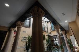 a lobby with columns and plants in a building at Hotel Boutique Casón De Los López in Toledo