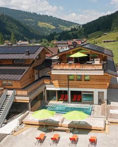 una casa con piscina, sedie e ombrelloni di Alpin Chalet Kleinarl a Kleinarl