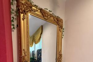 an ornate gold mirror on a wall with a window at 1 Bed Flat - Sleeps 5 - Pet friendly - Parking in South Shields