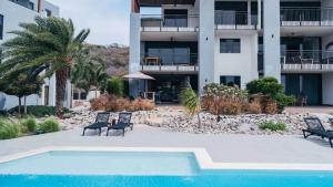a swimming pool with two chairs and a building at Holland House - Cape Marie 1401 in Willibrordus