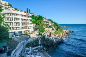 a building on a cliff next to the water at Hotel & Beach Club Mediterraneo Liman in Ulcinj