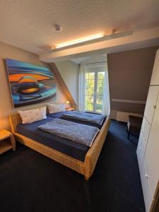 a bedroom with a bed with a painting on the wall at Ferienwohnung im Poolhaus mit Ostseeblick in Wittenbeck