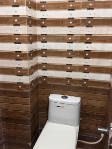 a toilet in a bathroom with wooden walls at Hotel Yash in Prayagraj