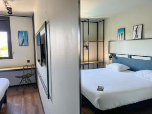 een hotelkamer met twee bedden en een televisie bij Ibis Lunel Petite Camargue in Lunel