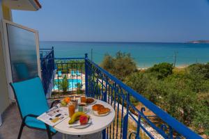 a table with food on a balcony with a view of the ocean at Milos Studios in Lourdhata