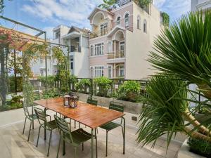 a wooden table and chairs on a patio with a building at The Midnight Lotus Saigon-Urban Retreat with Private Balcony-Free Laundry in Ho Chi Minh City