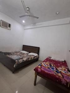two beds in a room with a ceiling fan at Vrindavan Homestay in Vrindāvan
