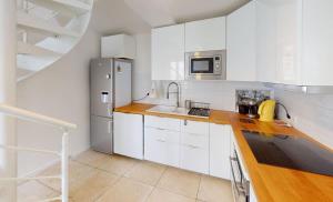 a kitchen with white cabinets and a stainless steel refrigerator at Charme, plage & tout à pied in Luc-sur-Mer +7 photos