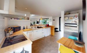 eine Küche mit weißen Schränken und einem Edelstahlkühlschrank in der Unterkunft Maison familiale entre mer et campagne in Putot-en-Bessin