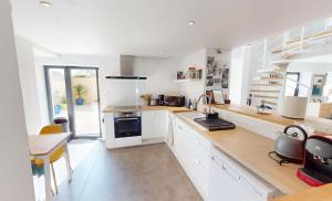 eine Küche mit weißen Schränken und einer Arbeitsplatte in der Unterkunft Maison familiale entre mer et campagne in Putot-en-Bessin + 24 Fotos