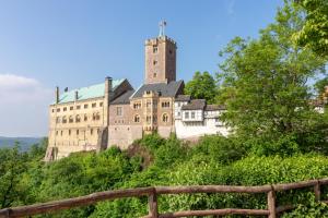 an old castle on a hill with a wooden fence at Glockenhof in Eisenach