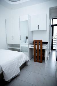 Un dormitorio blanco con una cama y un escritorio. en Blue sky apartment, en Kigali