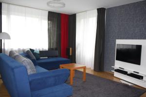 WahlershausenにあるDas Blaue Haus - Ferienwohnungの青いソファとテレビのあるリビングルーム +2枚の写真