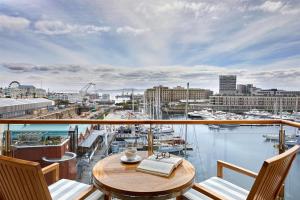 a balcony with a table and chairs and a view of a harbor at One&Only Cape Town in Cape Town