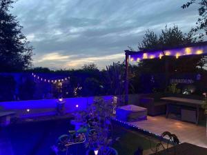 a patio with purple lights and a table and a fence at The Purrfect Creative Retreat in Gainsborough