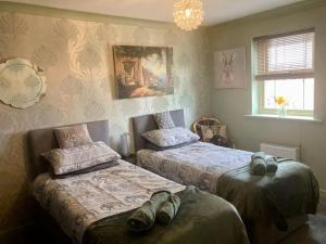 a bedroom with two beds and a chandelier at The Purrfect Creative Retreat in Gainsborough +22 photos