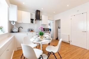 une cuisine et une salle à manger avec une table et des chaises blanches dans l'établissement New! Delightful 2BR Flat in Woolwich, à Plumstead