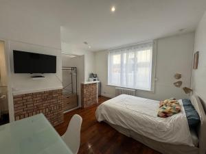 a bedroom with a bed and a tv on the wall at Le cottage des lumières in Boulogne-sur-Mer