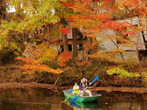 a man and a child in a boat on the water at クイーンズマウンテン ペット歓迎 温泉完備 一棟ログハウス 超体験型 貸別荘 ファミリーリゾート 乗馬 釣り ふれあい動物園 那須 那須町 in Nasu-yumoto