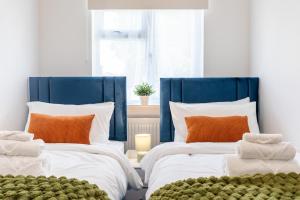 - 2 lits dans une chambre avec des oreillers bleus et oranges dans l'établissement New! Delightful 2BR Flat in Woolwich, à Plumstead 19 autres photos