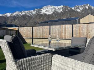a patio with a table with two wine glasses on it at Spa apartment in Queenstown in Queenstown Airport