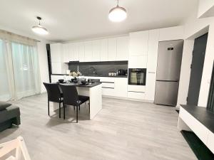 a kitchen with white cabinets and a table and chairs at Short Stay Cosbuc in Baia Mare