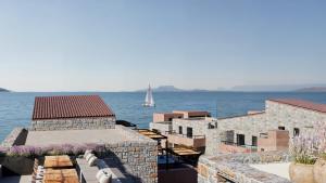 a sailboat in the water with buildings and the ocean at Volta Seaside Boutique Hotel in Kokkíni Khánion