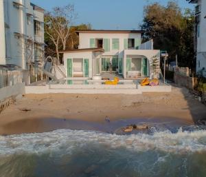 a house on the beach next to a body of water at Sea Sand Sun Pool Villa cha-am in Cha Am
