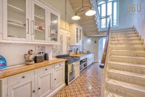 a kitchen with white cabinets and a staircase in the background at Lovely 4BR Maltese Home with Private Garden & BBQ by 360 Estates in Cospicua