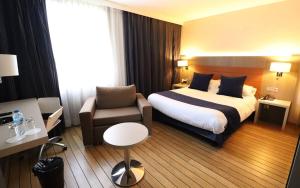 a hotel room with a bed and a chair at Logis Hôtel & Restaurant - Les Tuileries in Féy