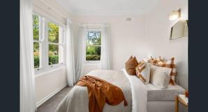 a white bedroom with a bed and two windows at Charming Cottage Walk to City and Eat Street in Braddon
