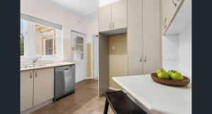 a kitchen with a bowl of green apples on a counter at Charming Cottage Walk to City and Eat Street in Braddon