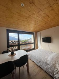 ein Schlafzimmer mit einem Bett, einem Tisch und einem großen Fenster in der Unterkunft Appartement centre des Carroz in Arâches-la-Frasse