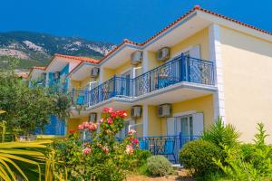 a building with blue balconies and flowers at Milos Studios in Lourdhata