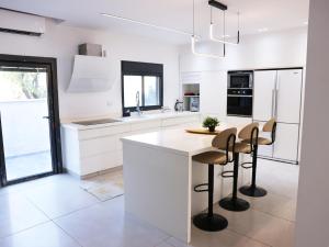 une cuisine avec des placards blancs et un îlot avec des tabourets de bar dans l'établissement וילה Mandala אירוח&אירועים, 